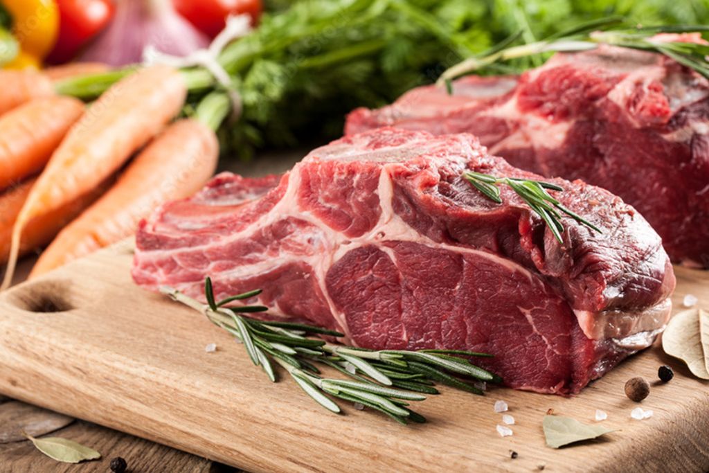 grass-fed beef steak on a cutting board with herbs surrounding it