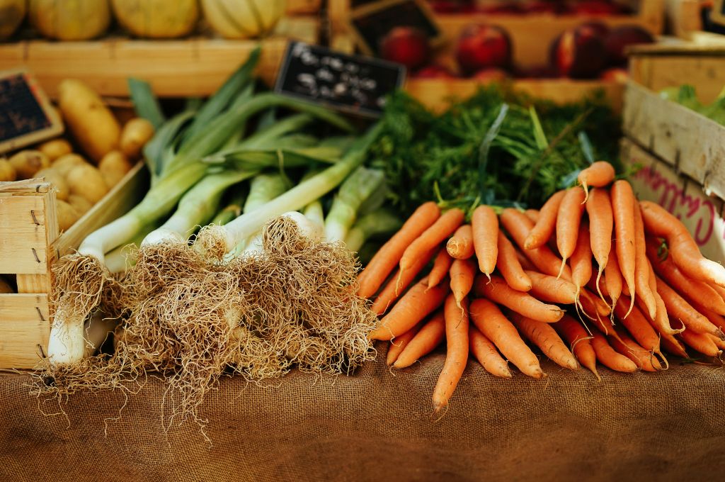 green onions and carrots featured in farm market produce stand on table